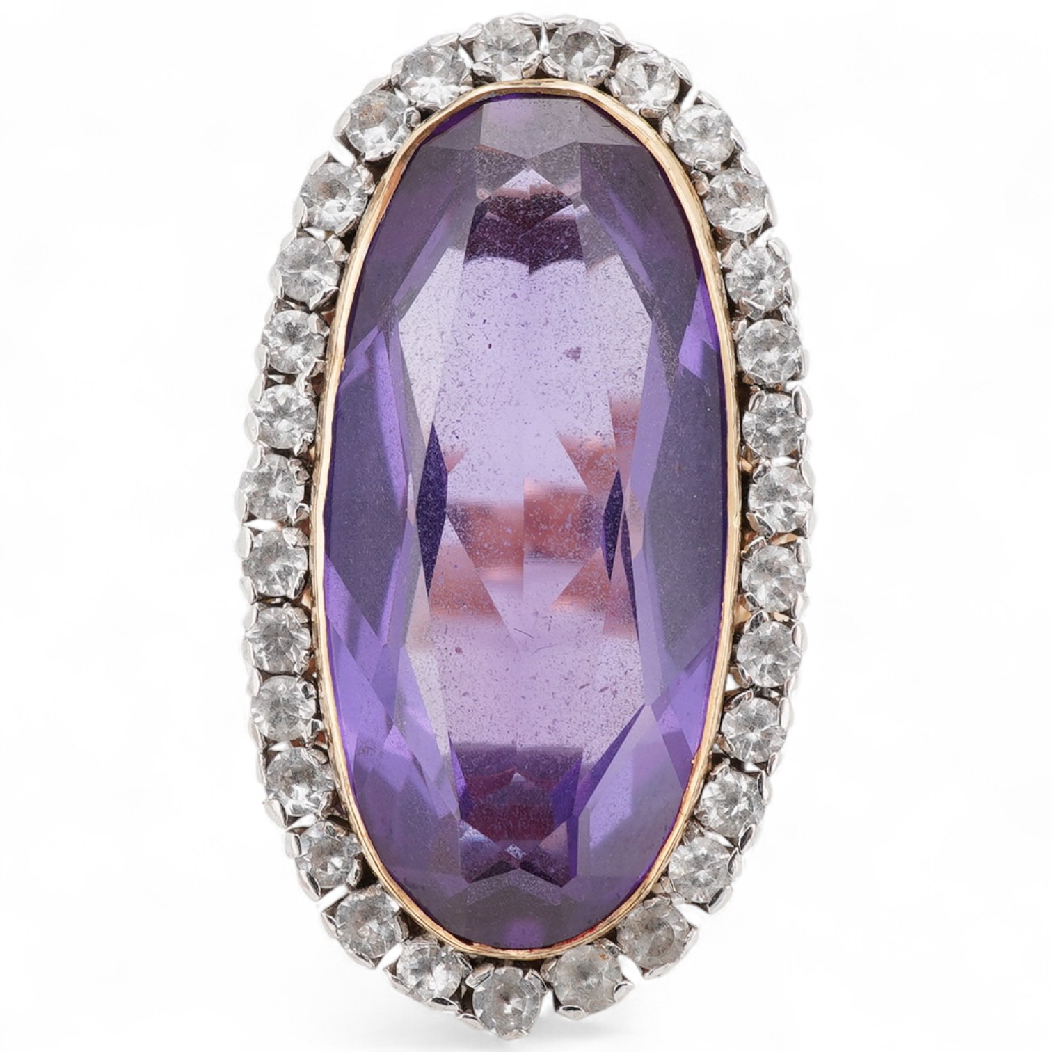 A synthetic colour change sapphire ring, set with an oval synthetic colour-change sapphire measuring approximately 27 x 12 x 6.4mm, within a border of simulant diamonds, mounted in silver and gold, size R, gross weight a